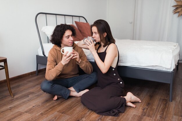 happy loving couple drink coffe together sit on floor