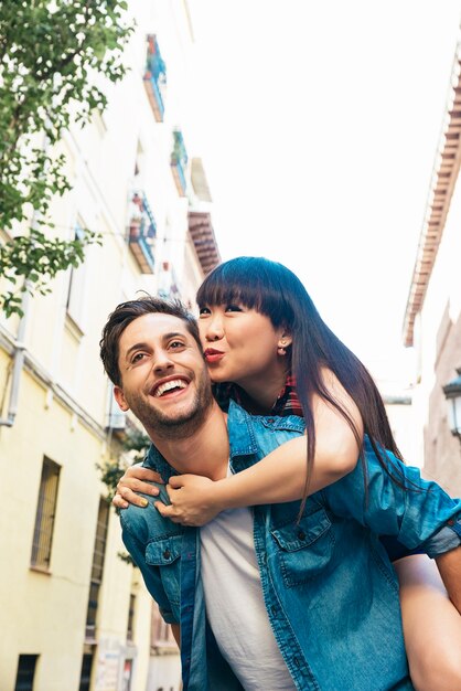 Happy loving couple. Happy young man piggybacking his girlfriend while hug he