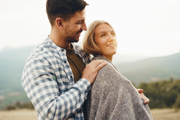 Happy loving couple hiking and hugging in mountains