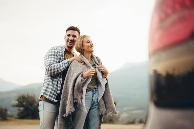 Happy loving couple hiking and hugging in mountains