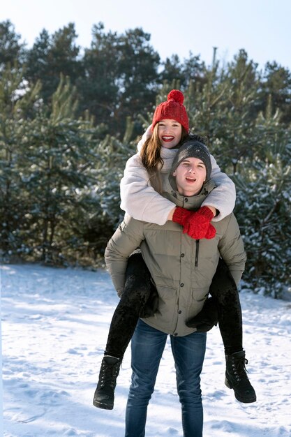 Happy loving couple is having fun in winter outdoors Guy rolls girl on his back