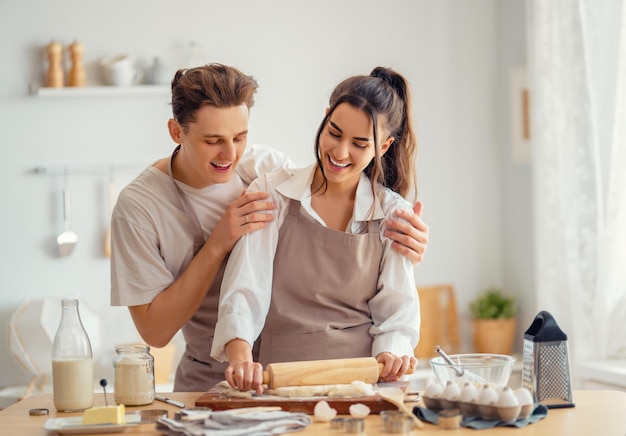 Happy loving couple is preparing the pastry in the kitchen.