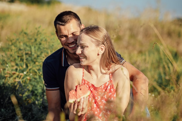 Happy loving couple kissing and having date outdoors young couple on summer picnic with watermelon