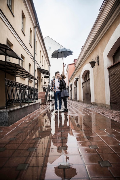 Happy loving couple kissing under an umbrella on a city street on a rainy day