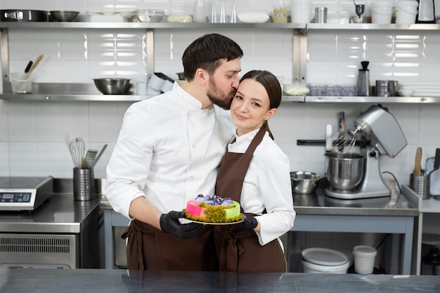 Felice amorevole coppia di pasticceri un uomo e una donna tengono in mano una torta di mousse