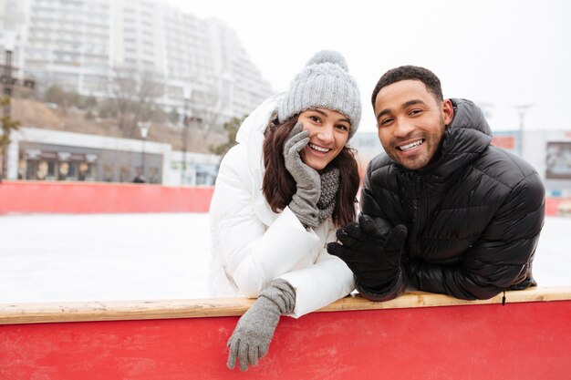 Happy loving couple skating at ice rink outdoors.