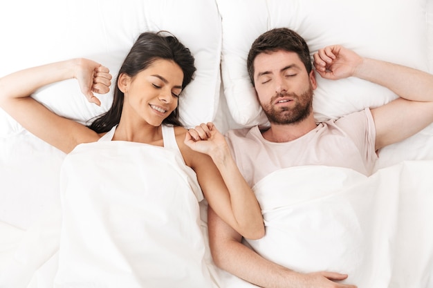 a happy loving couple sleeping in bed under blanket