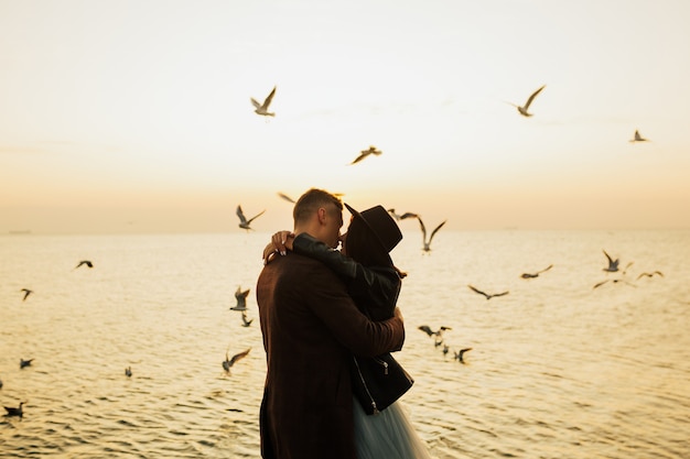 Happy loving couple in stylish clothes posing on a pier near sea.