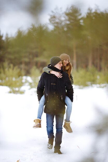 눈 덮인 겨울 숲에서 함께 야외에서 걷는 행복 한 사랑 부부