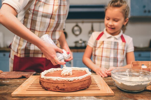 Happy loving family are preparing bakery together. Mother and child daughter girl having fun in the kitchen. Proudly holding freshly baked Homemade pie.