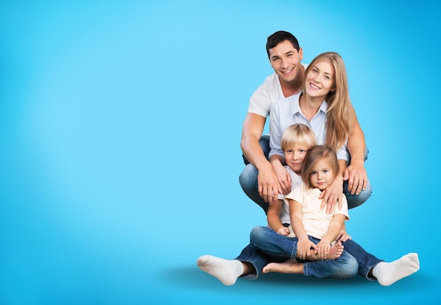 Счастливая любящая семья. Мужчина, женщина и ребенок сидят на полу в синей студии.