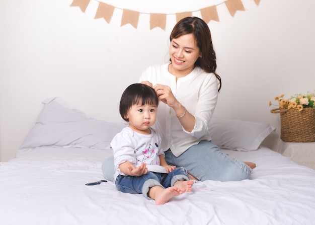 幸せな愛情のある家族。ママと子供の女の子はベッドで楽しんでいます。