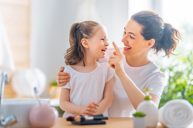 Happy loving family. Mother and daughter are doing make up and having fun.