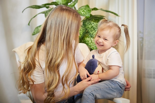 Happy loving family mother and her daughter child girl playing and hugging in living room with