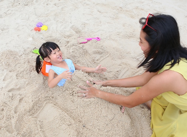 Happy loving family. Mother and her daughter child girl playing sand at the beach