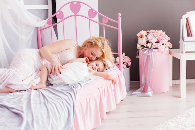 Happy loving family. Mother and her daughter laying on a bed in a girly room