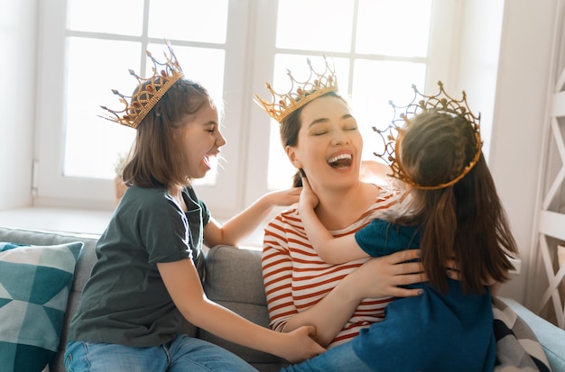 Happy loving family. Mother and her daughters children girls playing and hugging at home.