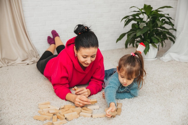 Счастливая любящая семья играет с деревянными блоками и веселится. Мать и ее дочь играют вместе.