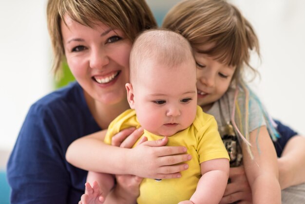 Happy loving family. portrait of young mother with  her kids little girl and baby boy hugging each other while spending time together at home