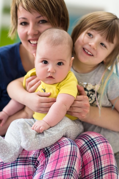 Happy loving family. portrait of young mother with  her kids little girl and baby boy hugging each other while spending time together at home