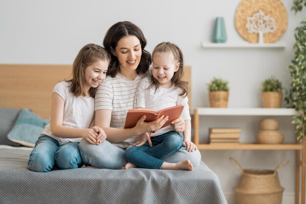 Famiglia amorevole felice. bella giovane madre che legge un libro alle sue figlie