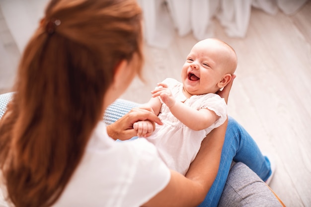 幸せな愛情のある家族の若い母親が寝室で彼女の子供と遊ぶ