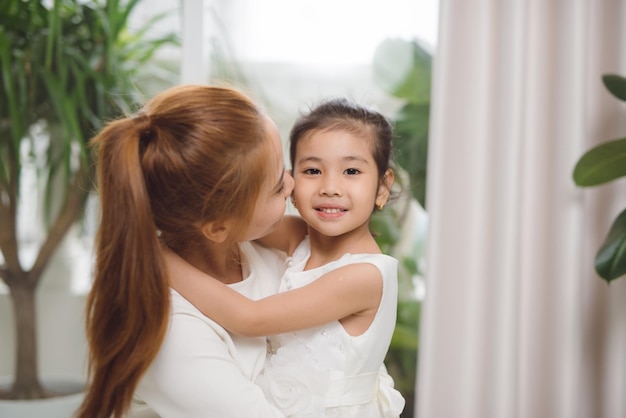 幸せな愛情のある家族アジアの母と子の女の子がキスとハグをして遊ぶ