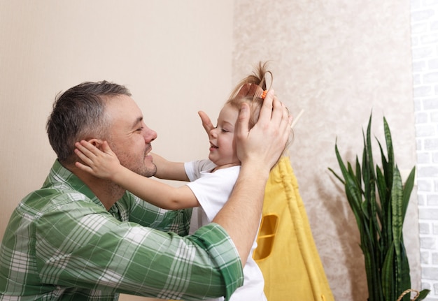 Foto un padre felice e amorevole gioca a casa con la sua piccola figlia