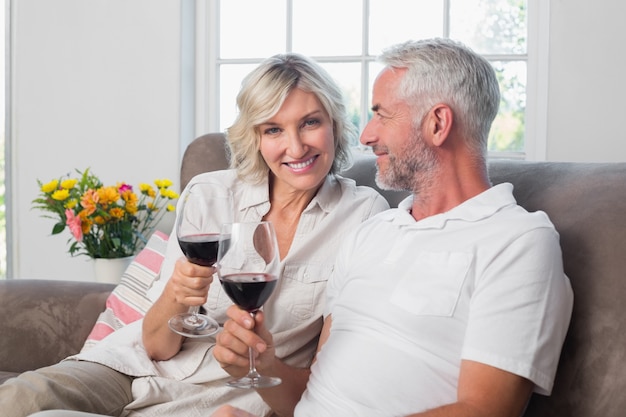 Happy loving mature couple with wine glasses in living room