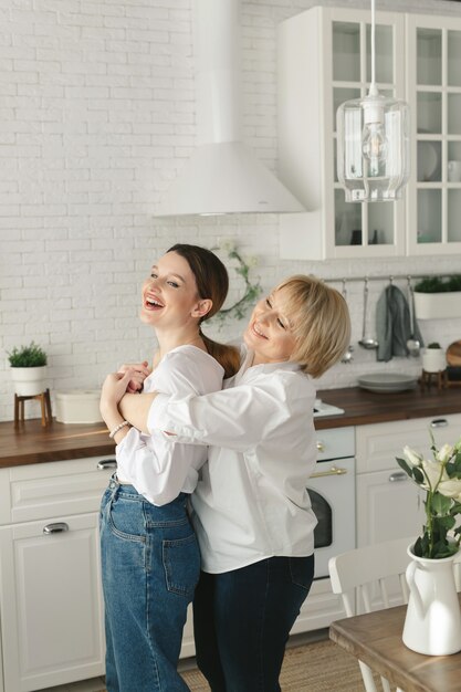 Happy loving older mature mother and grown daughter laughing embracing,