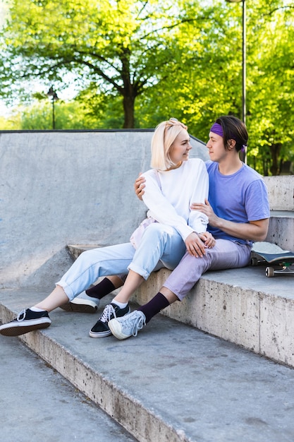 Happy and loving teenage couple in a skatepark