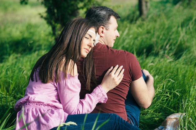 Happy loving young couple spending time in the park sitting on a green lawn on a sunny summer day