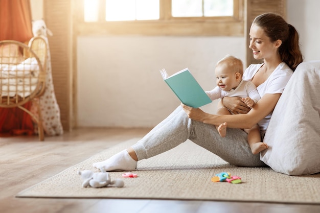 幸せな愛情のある若い母親と彼女の赤ちゃんの息子が本を読んで