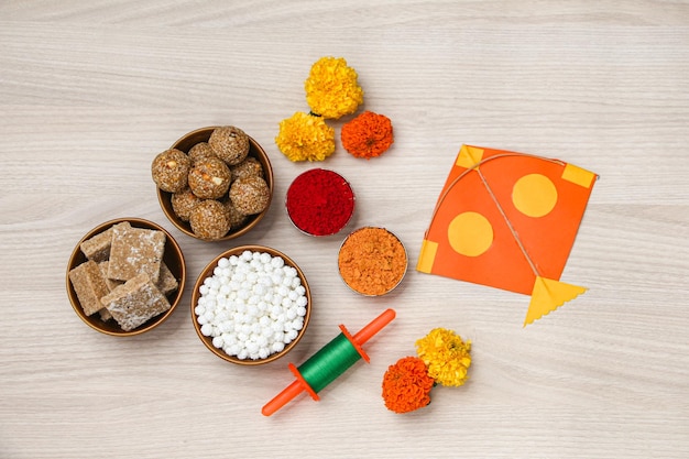 Happy Makar Sankranti, Pongal 및 Uttarayan with Kite, haldi kum kum bowls and tilgul sweets