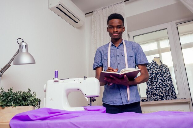 Happy male african designer constructor engineer writing down ideas in a notebook in studio