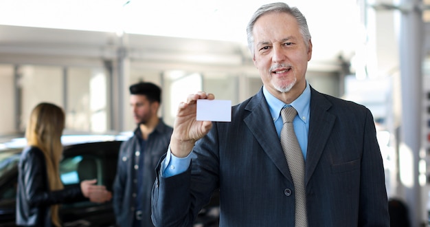 Photo happy male car dealer holding a business card