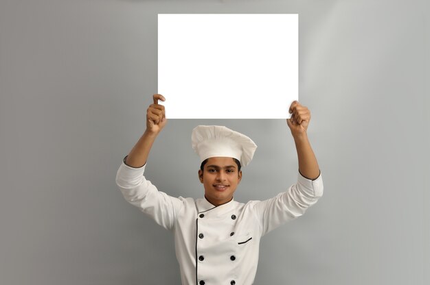 Photo happy male chef dressed in uniform holding white advertising banner good poster for ad