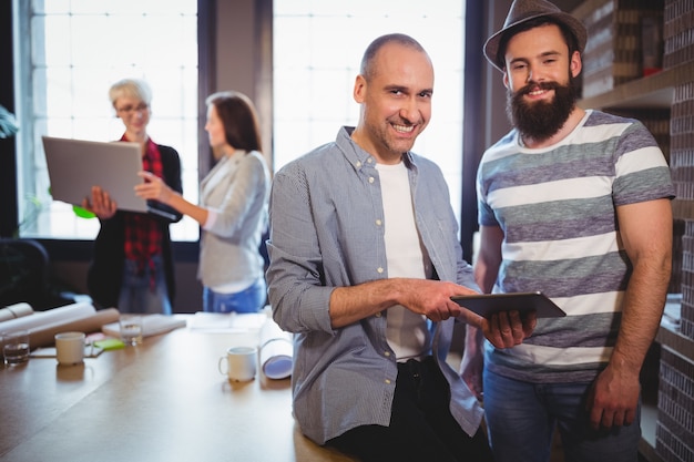 Happy male colleagues by desk in creative office