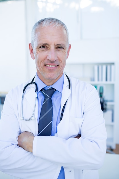 Happy male doctor looking at camera with arms crossed