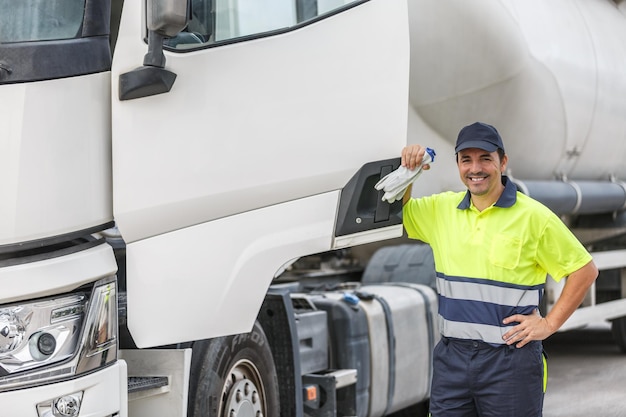 Happy male driver in uniform smiling while standing by truck