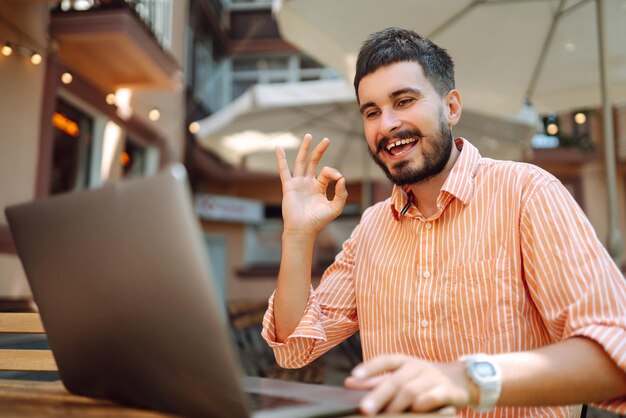 Photo happy male freelancer smiling while working at laptop with phone online conference blog concept