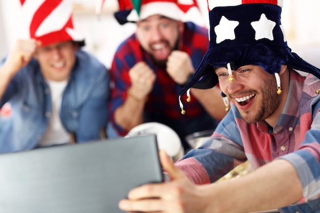 happy male friends cheering and watching sports on tv