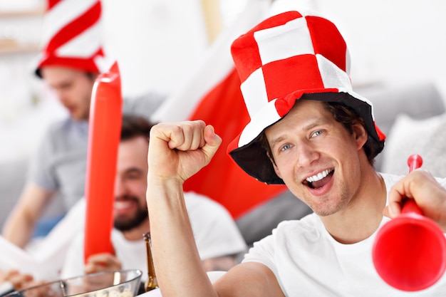 Photo happy male friends cheering and watching sports on tv