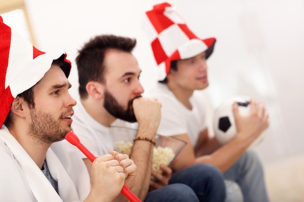 happy male friends cheering and watching sports on tv