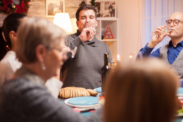 Happy male and his father drinking a glass of wine at christmas family dinner.