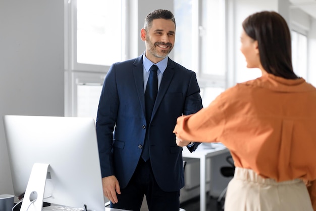 Foto felice responsabile del personale maschile e candidata al lavoro femminile che si stringono la mano dopo un colloquio di lavoro riuscito in ufficio