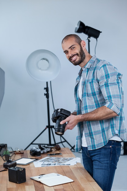 Счастливый мужской фотограф, стоя в студии