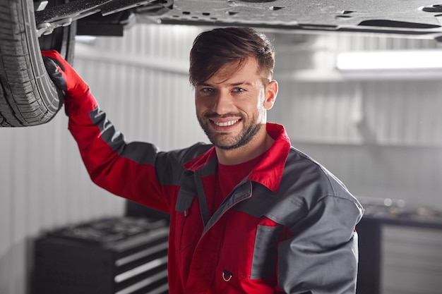 Happy male technician under car