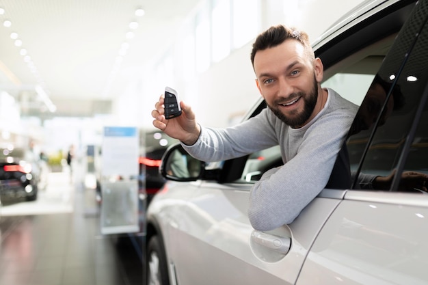 Happy man bought a car in a car dealership and insurance for it