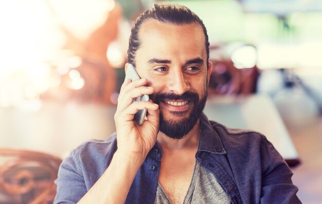 happy man calling on smartphone at bar or pub